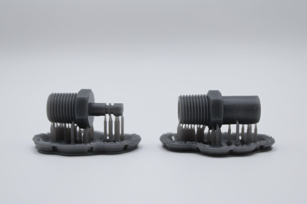 Dos piezas impresas en 3D con sus soportes de impresión